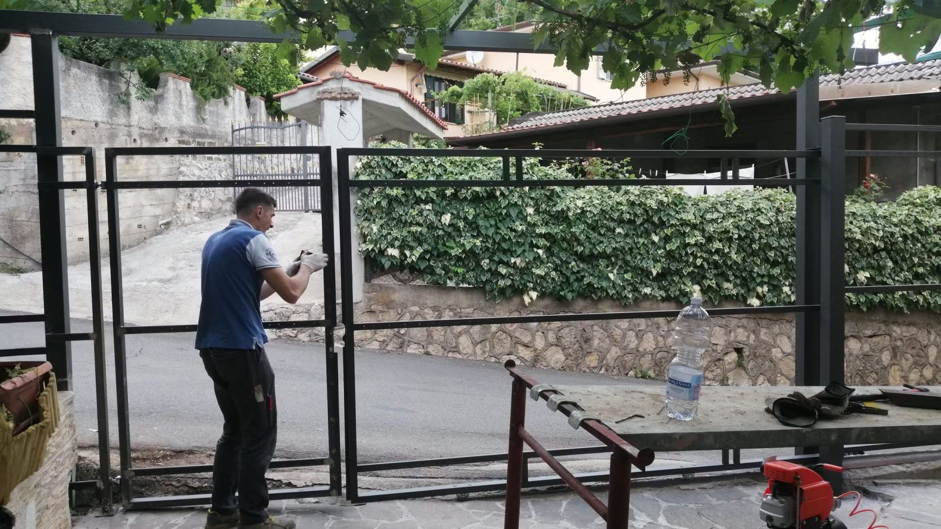 Un uomo sta lavorando su un cancello con un trapano.
