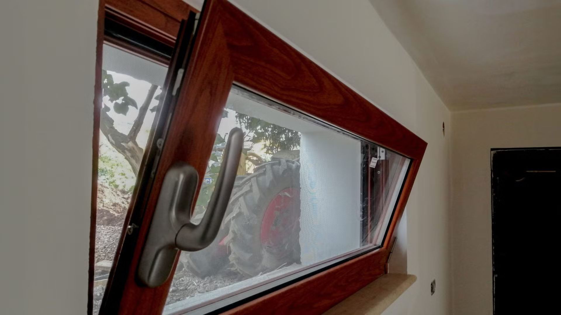 In una stanza è aperta una finestra di legno con una maniglia di metallo.