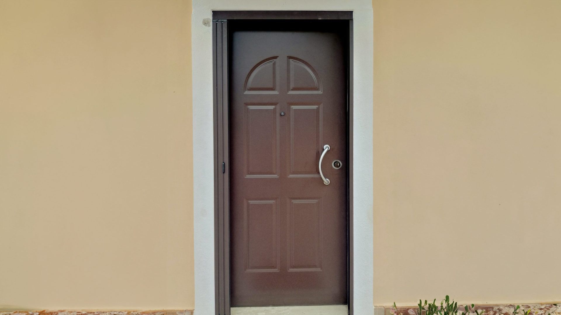 C'è una porta marrone sul lato di una casa.