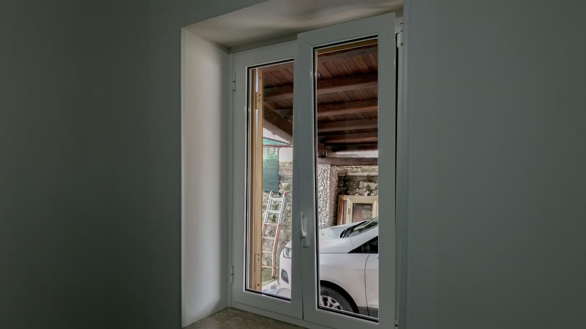 Un'auto bianca è parcheggiata in un garage accanto a una finestra.