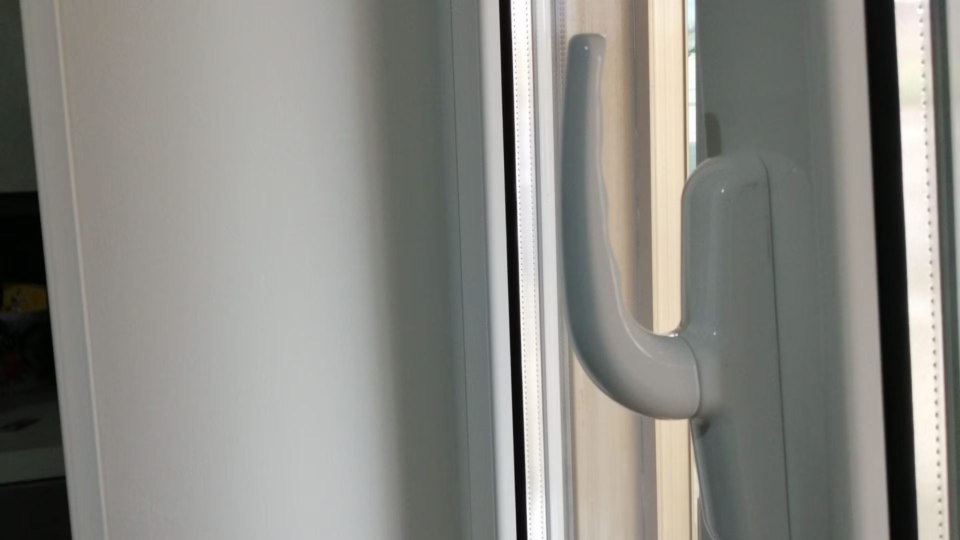 Un primo piano della maniglia bianca di una finestra bianca.