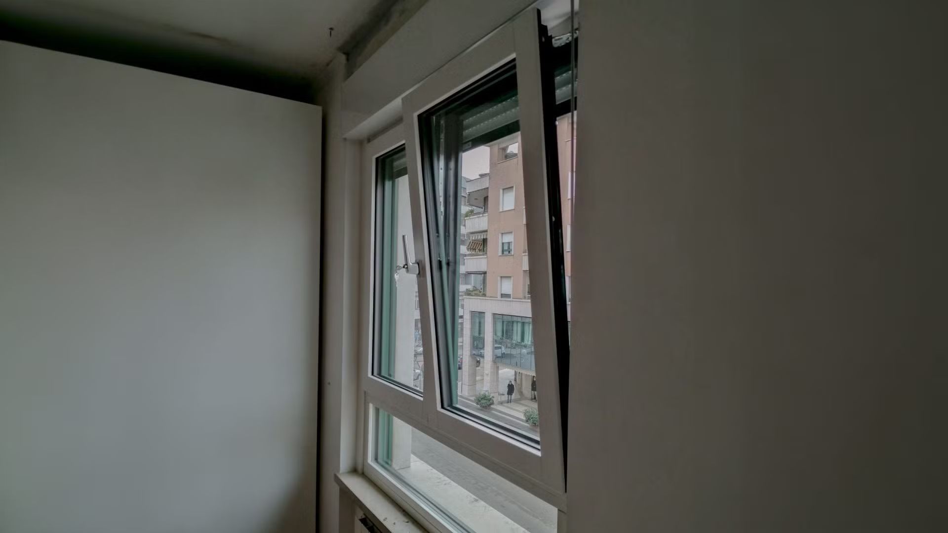 Una finestra è aperta in una stanza con una parete bianca.
