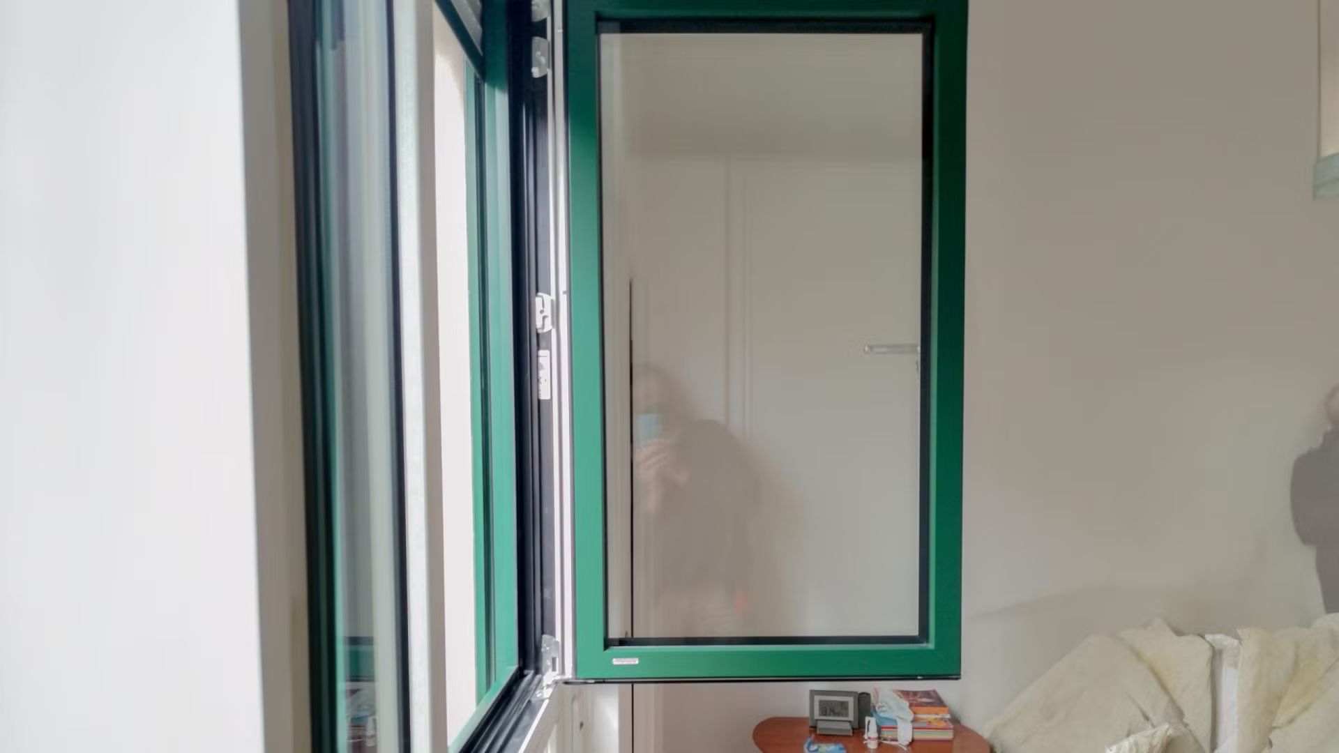 Una stanza con una finestra verde e una parete bianca.