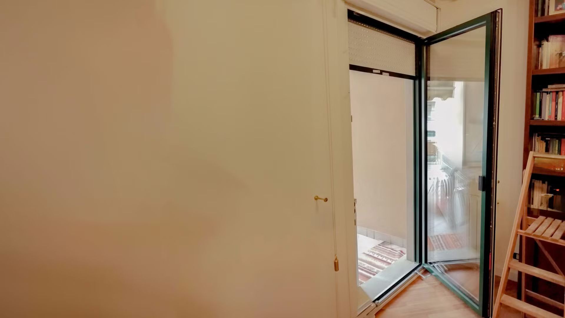 Una stanza con una porta scorrevole in vetro e una libreria.