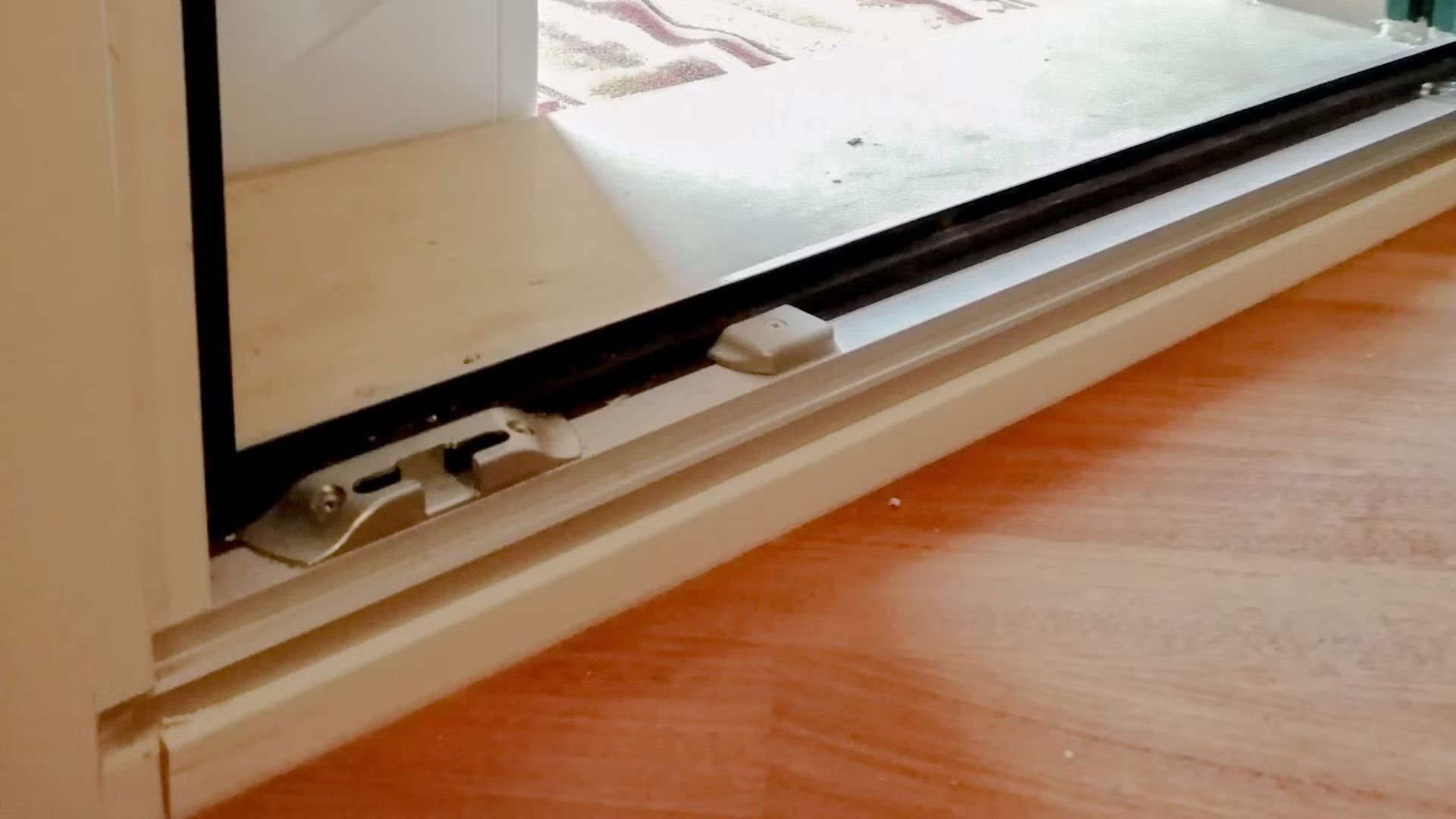 Primo piano di una porta scorrevole in vetro su un pavimento in legno.