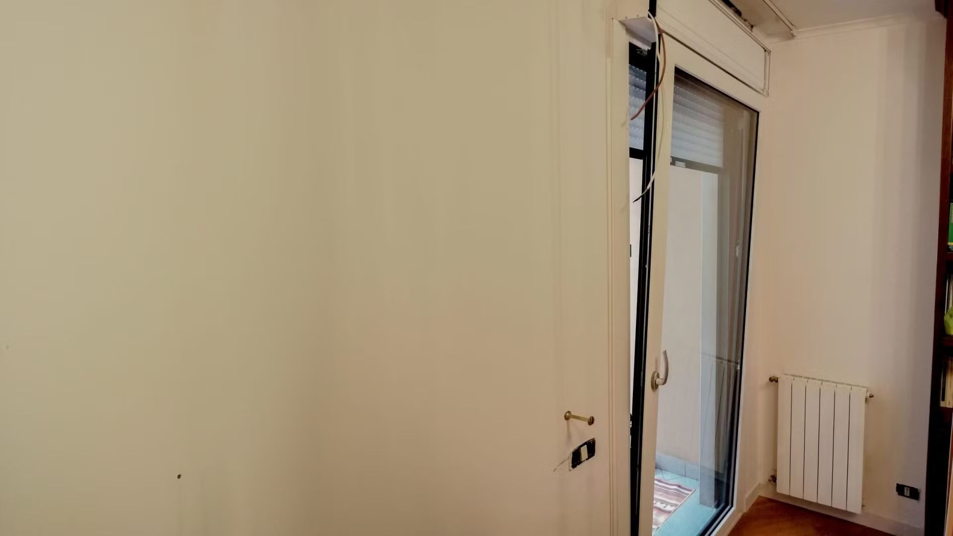 Una stanza con una porta scorrevole in vetro e un termosifone.