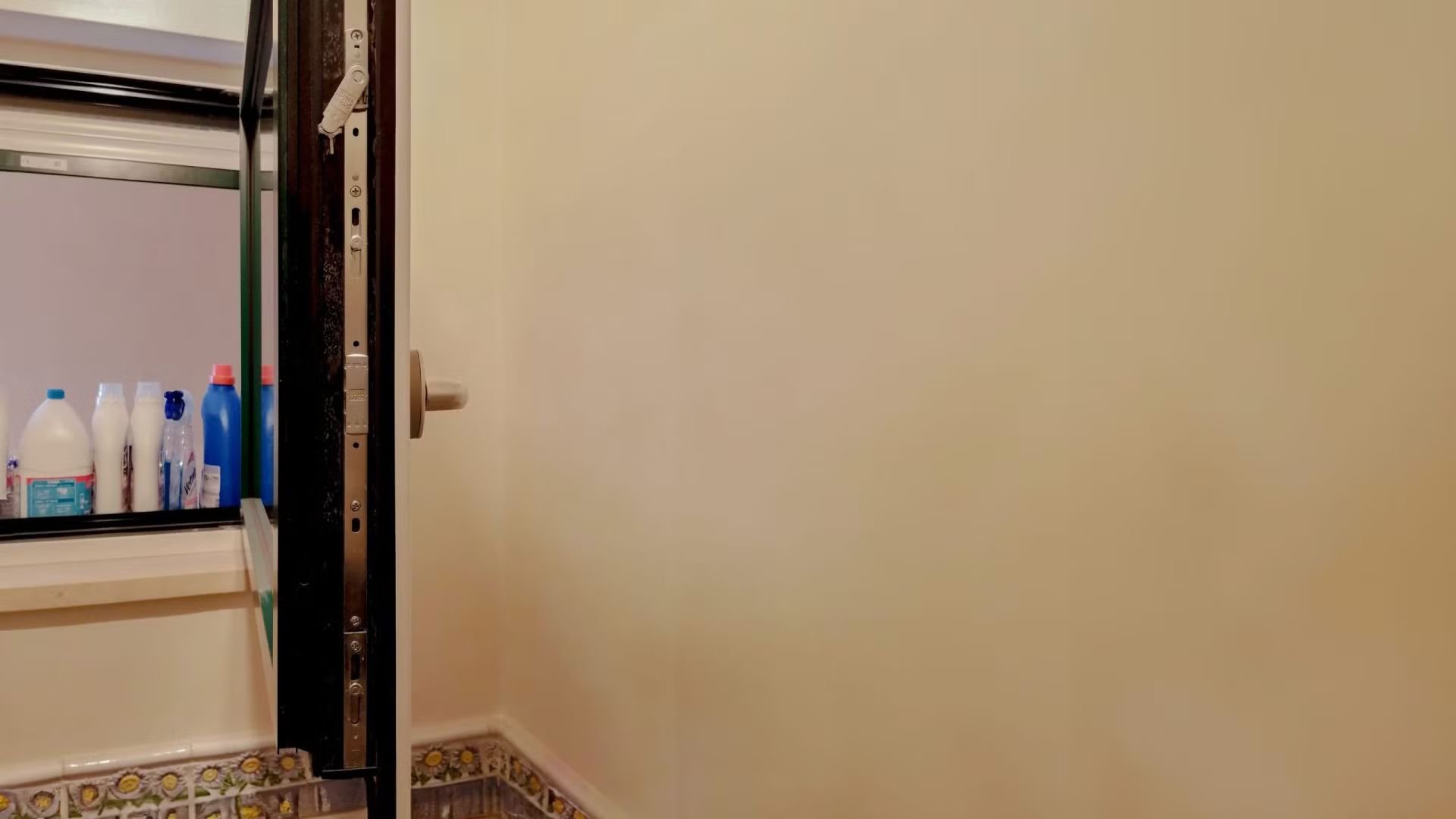 Un bagno con una porta aperta e uno scaffale con delle bottiglie sopra.