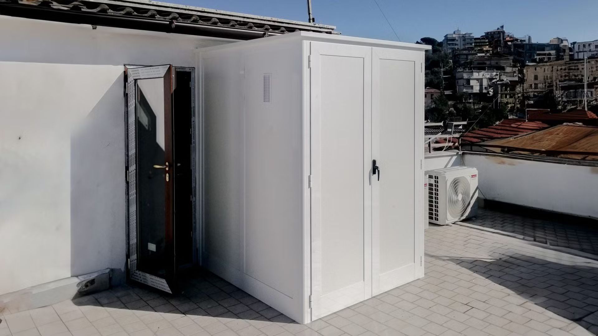 Un capannone bianco con una porta e un condizionatore d'aria sul tetto