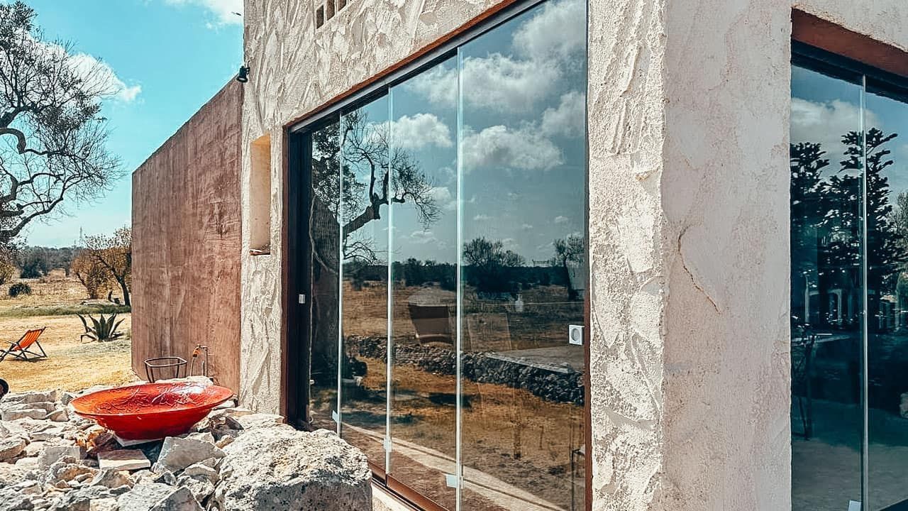 Una grande finestra sul lato di un edificio in cui si riflettono gli alberi.
