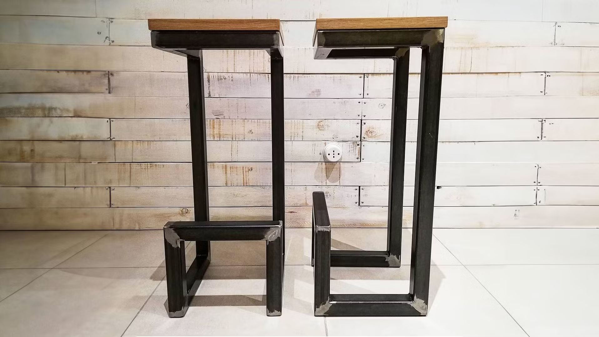 Due sgabelli da bar sono posizionati uno accanto all'altro davanti a una parete di legno.
