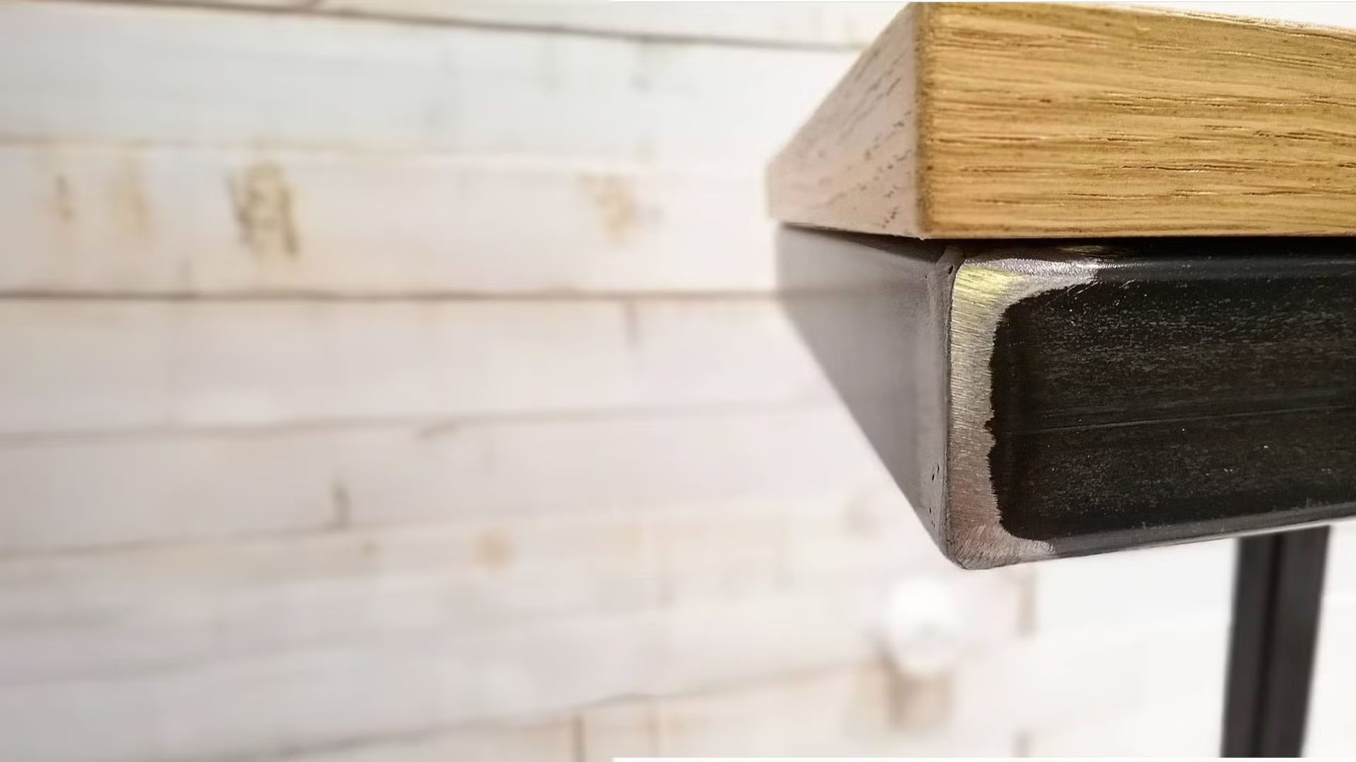 Primo piano di un tavolo con piano in legno e struttura in metallo.