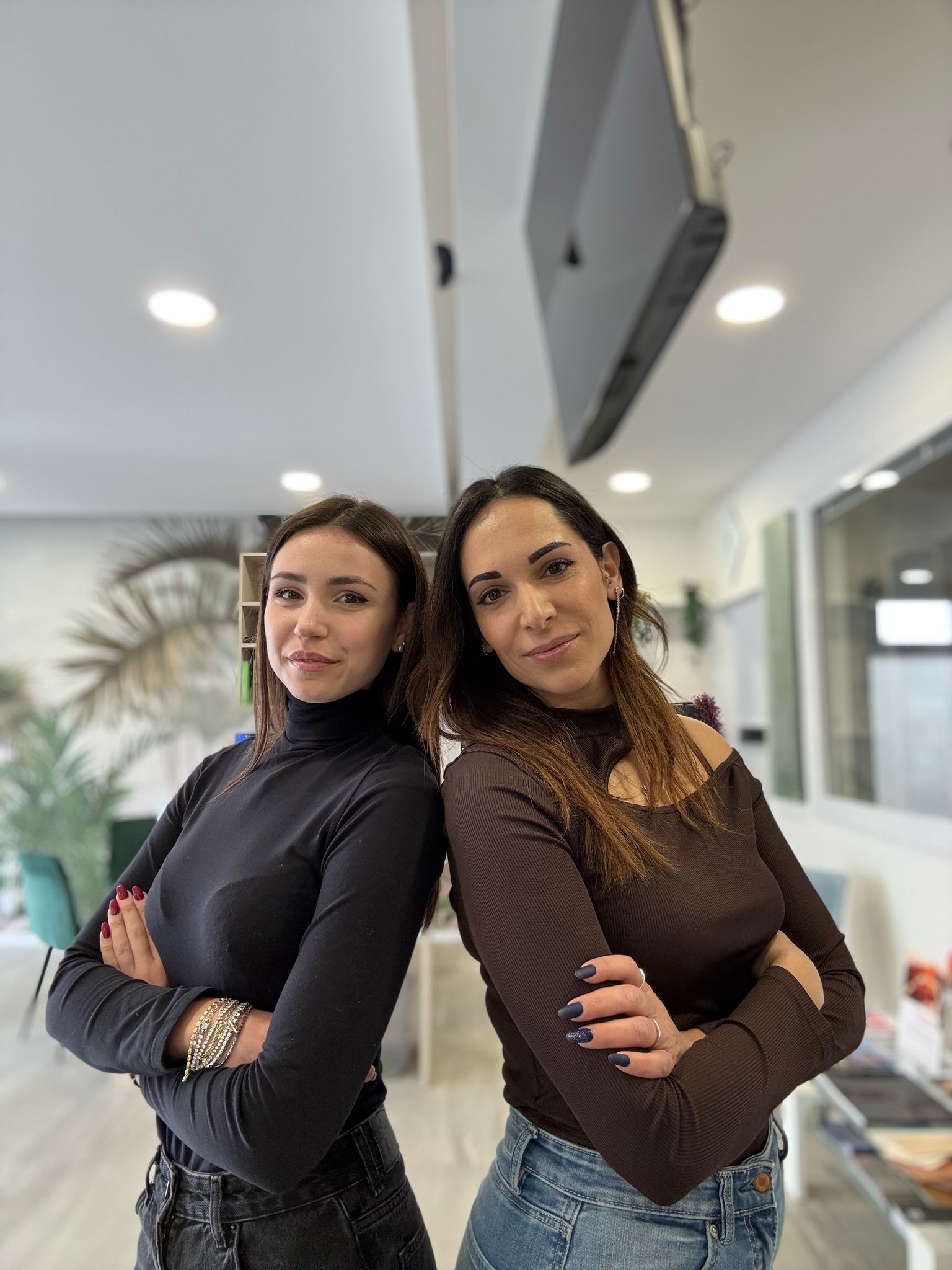 Una donna con una giacca a quadri posa per una foto con le braccia incrociate.