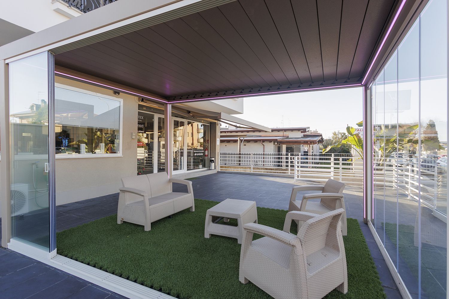 Un patio con un divano, sedie e un tavolo sotto un pergolato.