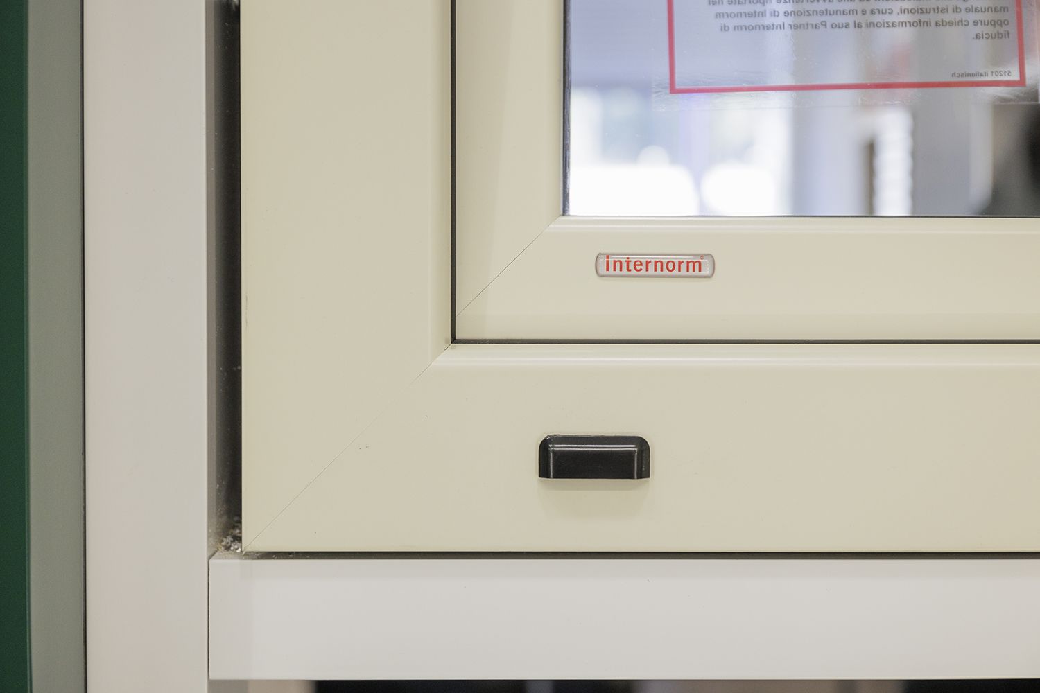 Un primo piano di una finestra bianca con una maniglia nera.