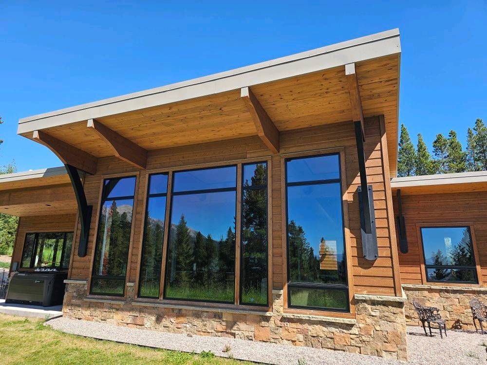 A large wooden house with a lot of windows and trees in the background.