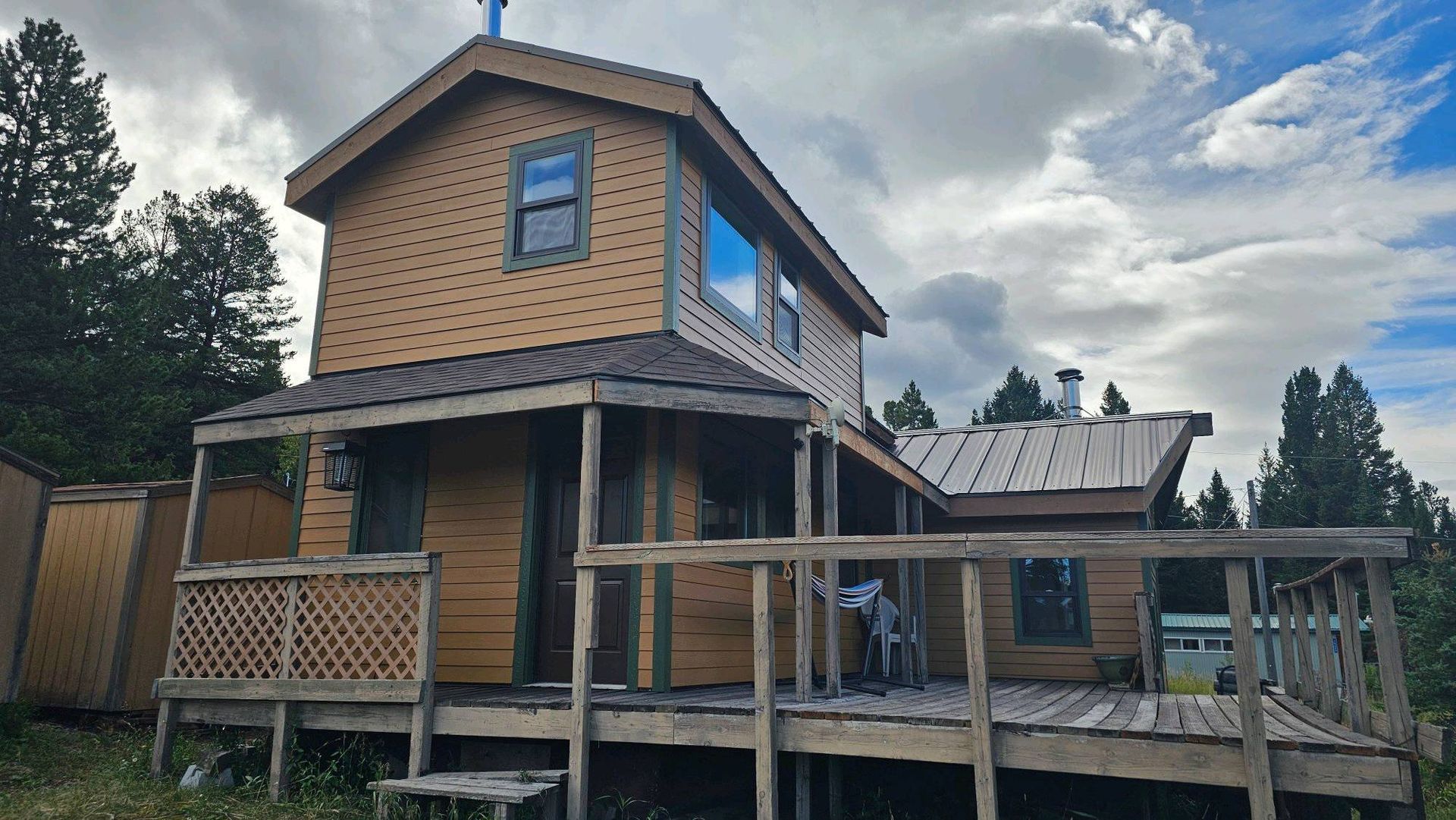 A small wooden house with a deck in the middle of the woods
