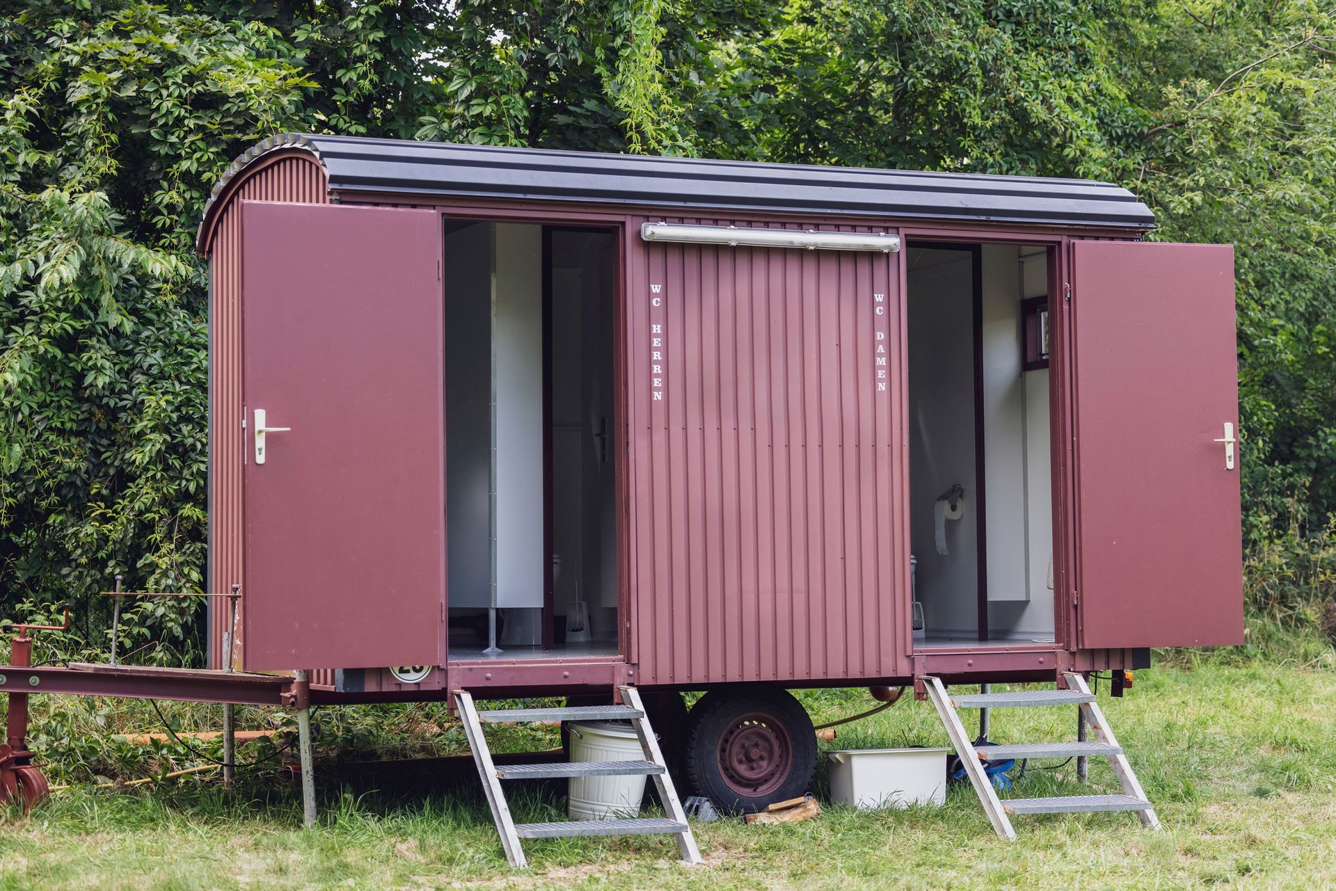 Red mobile restroom with open doors and steps. Red mobile restroom with open doors and steps.
