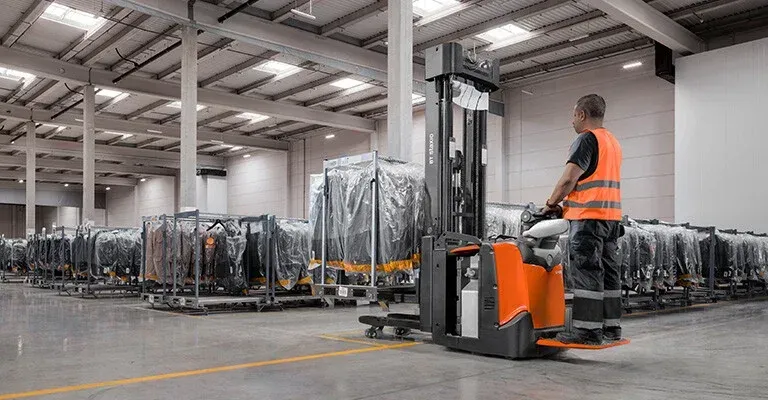 A man is driving a forklift in a warehouse.