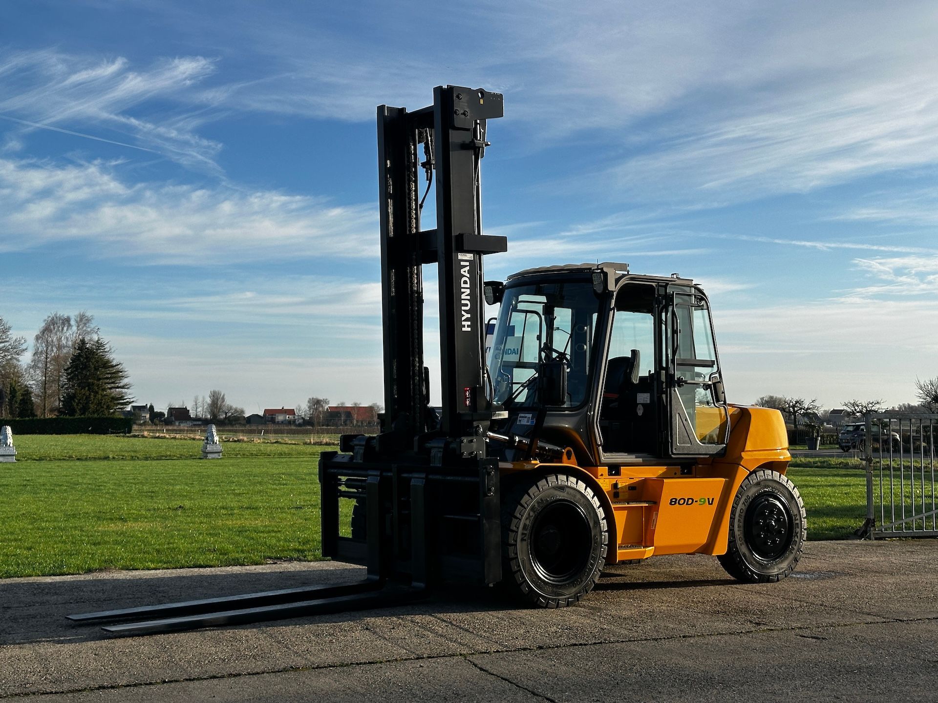 A yellow forklift is parked on the side of the road