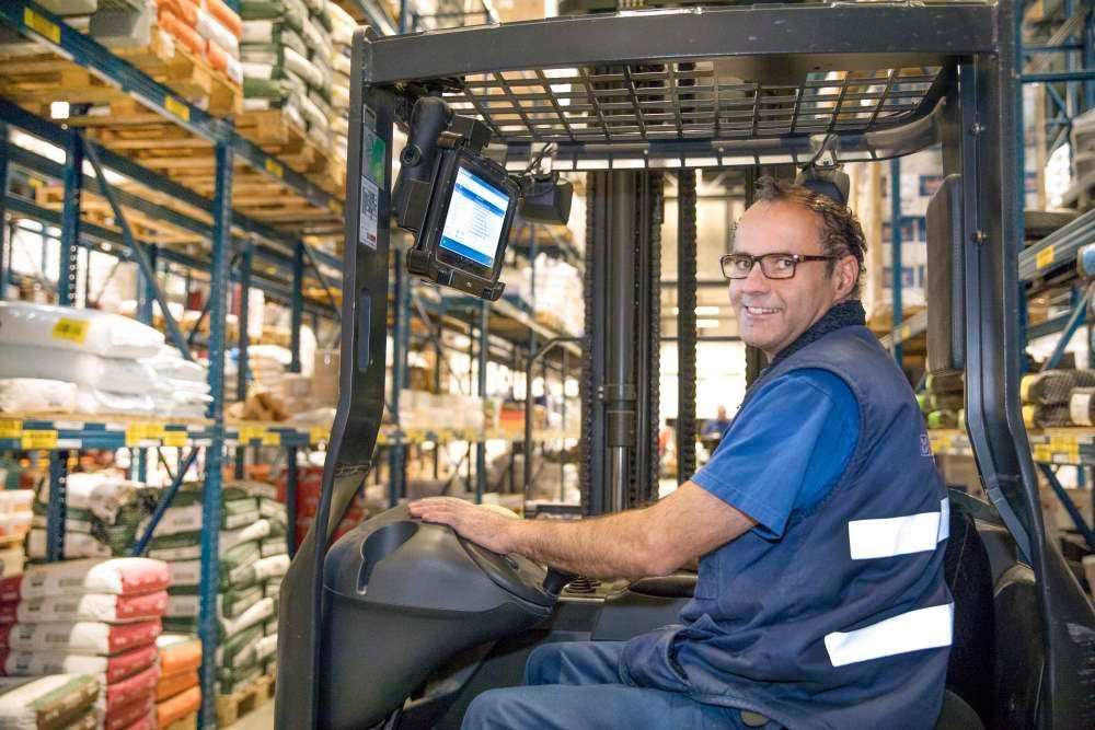 A man is driving a forklift in a warehouse.