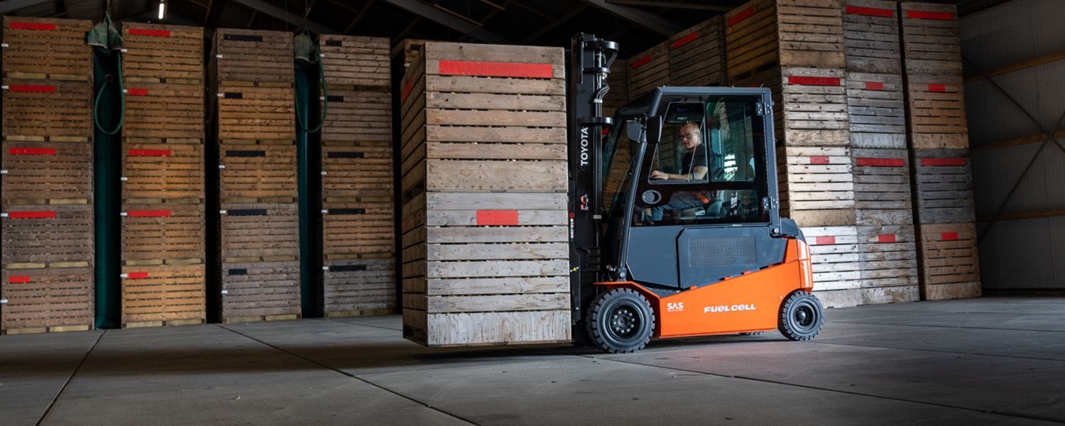 A forklift is carrying a large wooden box in a warehouse.