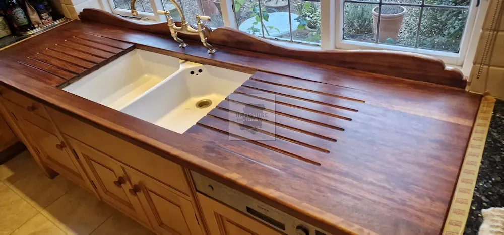 Wooden kitchen countertop with built-in double sink and drainboard in front of a window.