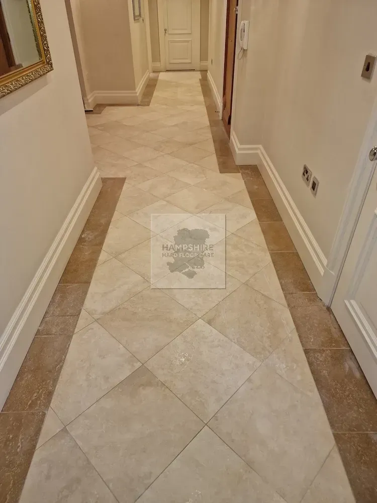 Hallway with light beige tiled floor, beige border, and white walls.