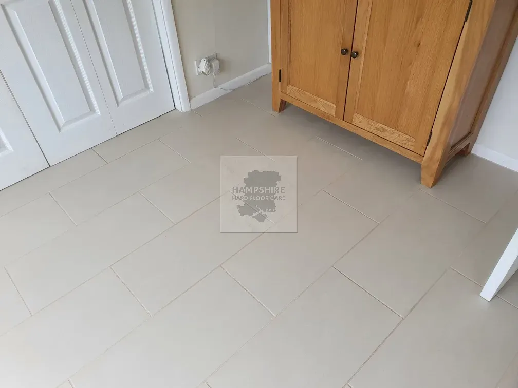 Beige tiled floor with wooden cabinet and white door.