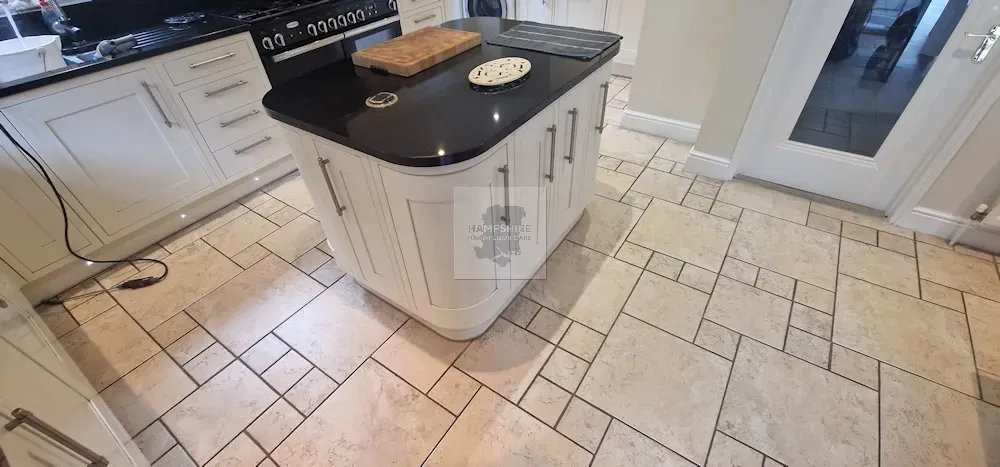 Kitchen with white cabinets, black countertop, island, and tiled floor.
