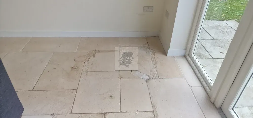 Light beige stone tiled floor, next to a white door frame and white wall.