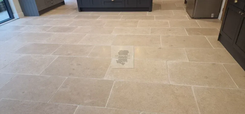 Beige stone tile floor in a room, with dark cabinets in the background.