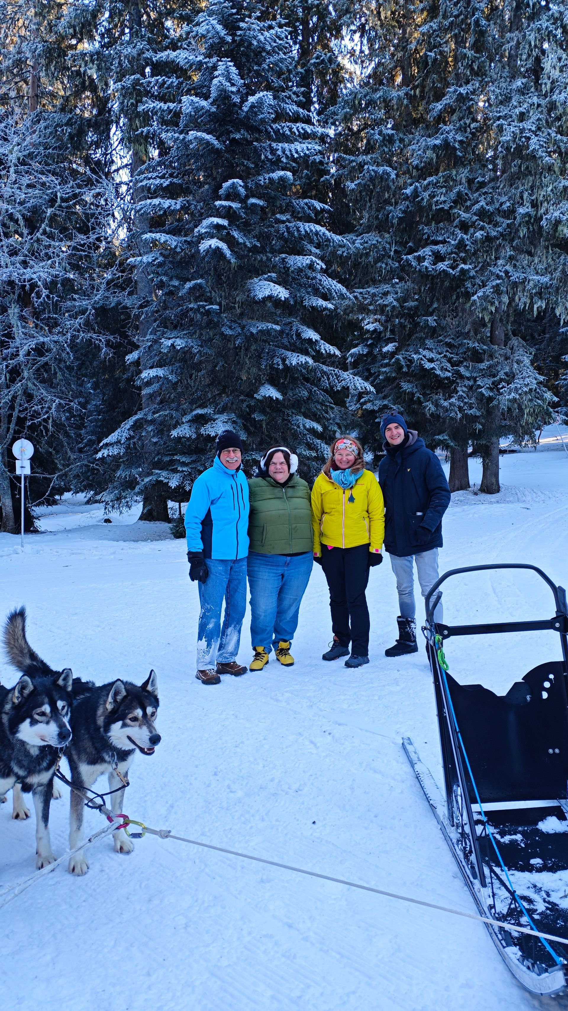 A group of people standing in the snow next to a sled.