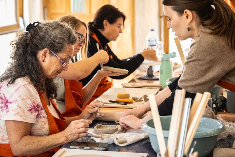 A woman is sitting on a pottery wheel making a bowl.