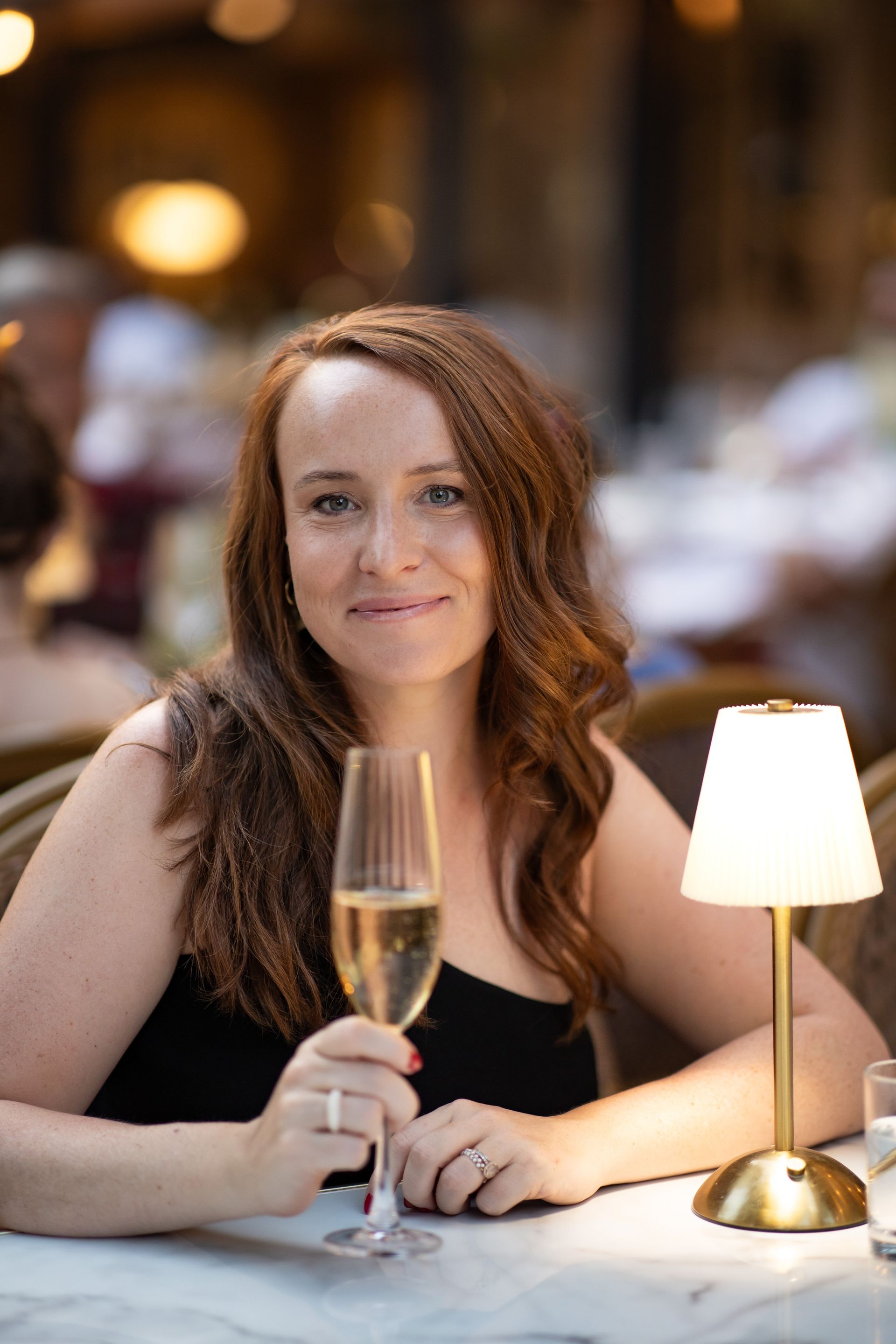 A woman wearing a hat and a zebra print shirt is smiling in a black and white photo.