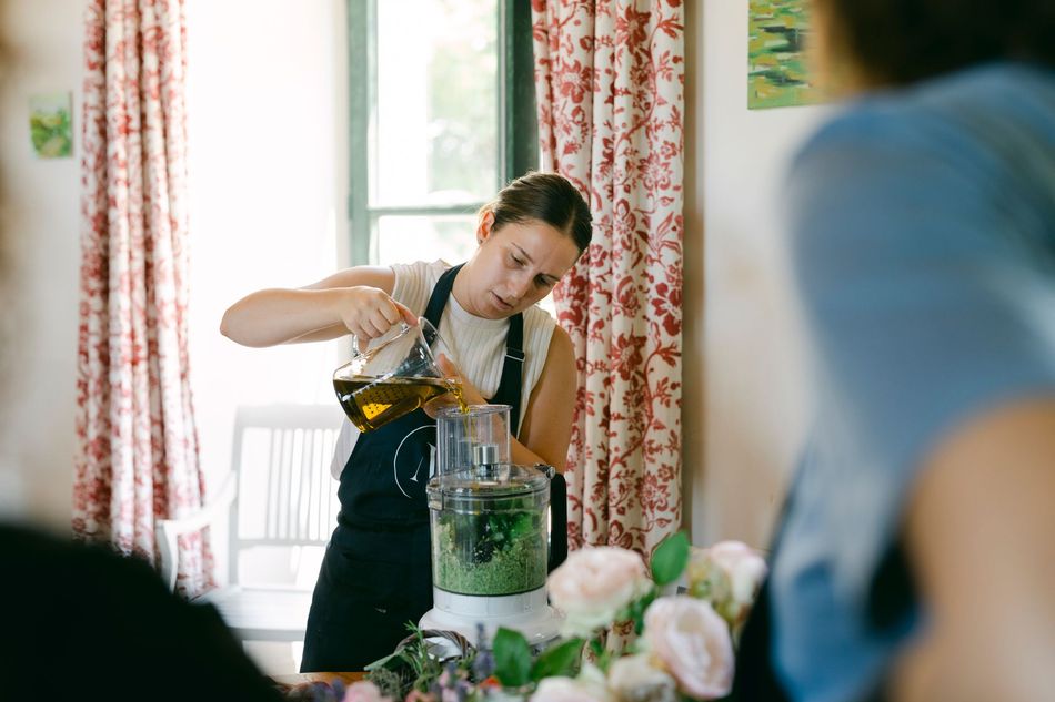 A person is pouring champagne into two glasses in a vineyard.