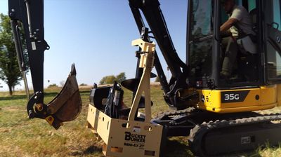 A yellow mini-excavator with the number 35g on it and a Bucket Bunker mounted to it's front blade