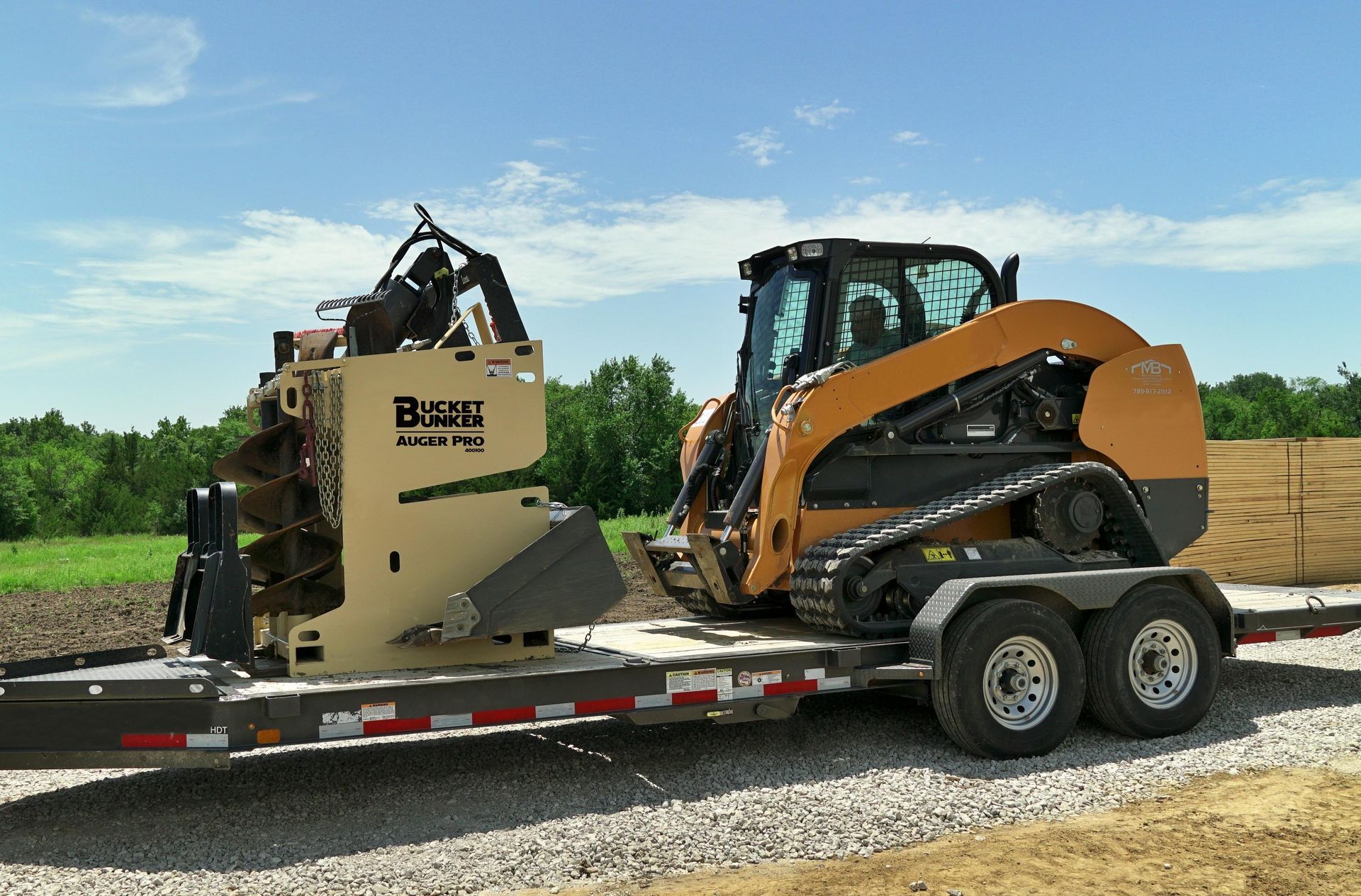 A skid steer and a mobile attachment rack by Bucket Bunker® loaded on a trailer ready to head to the jobsite.