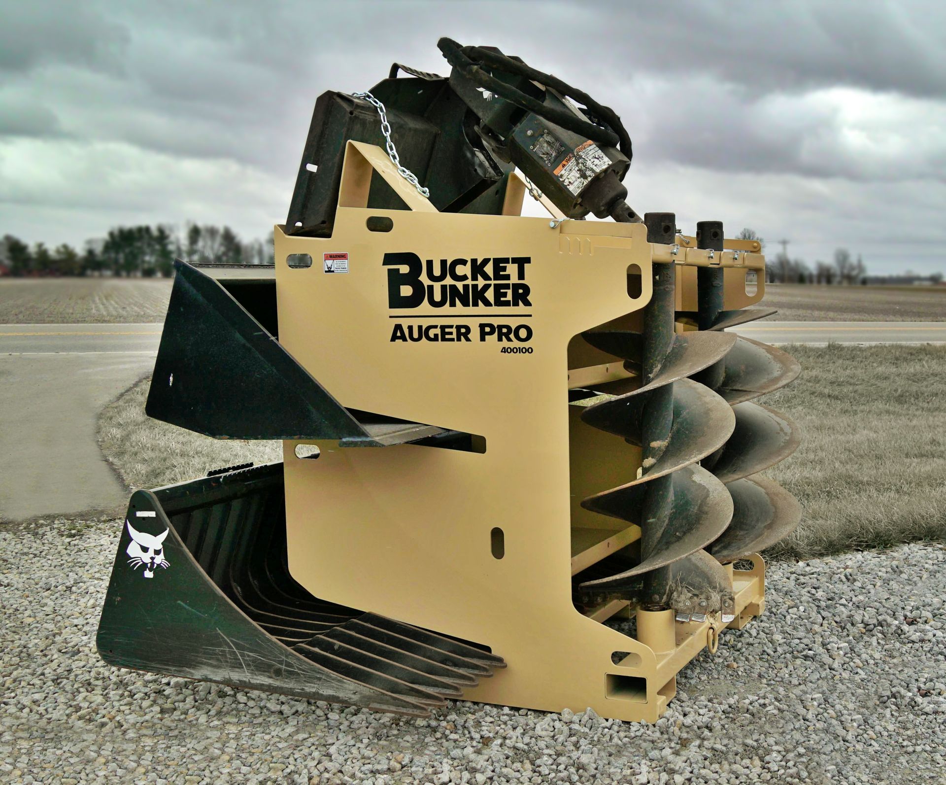 A bucket bunker auger pro is sitting on gravel