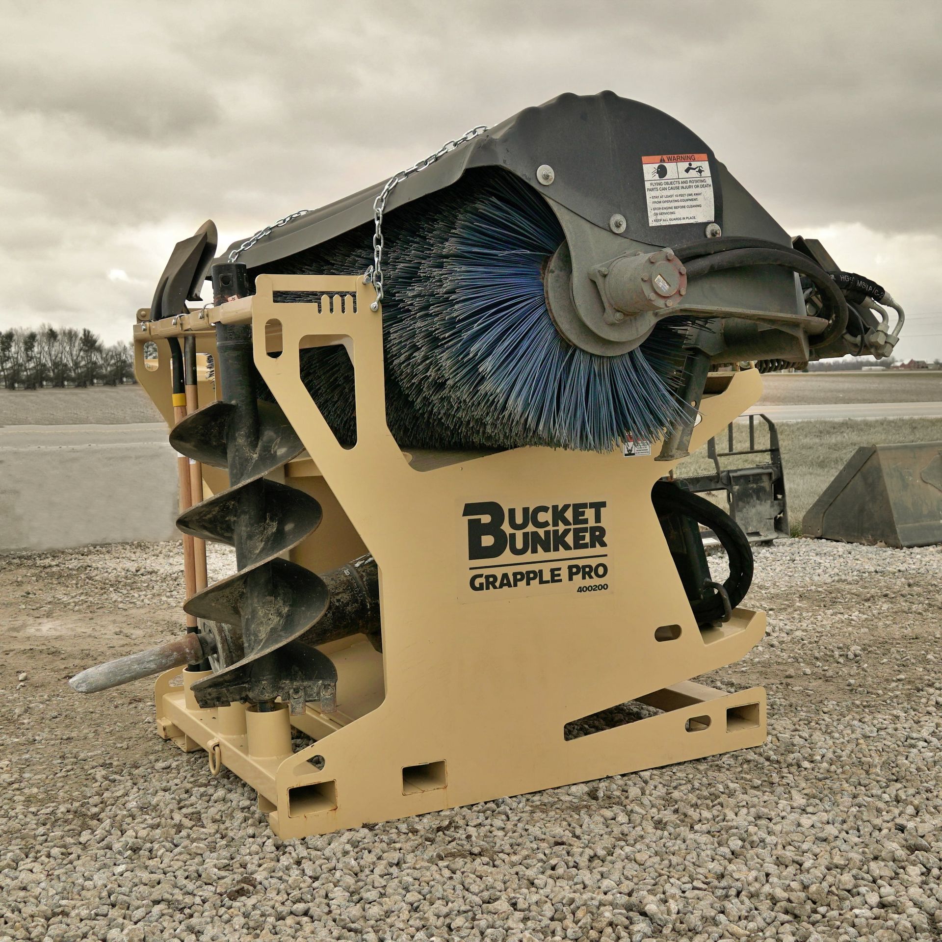 A bucket bunker grapple pro is sitting on gravel