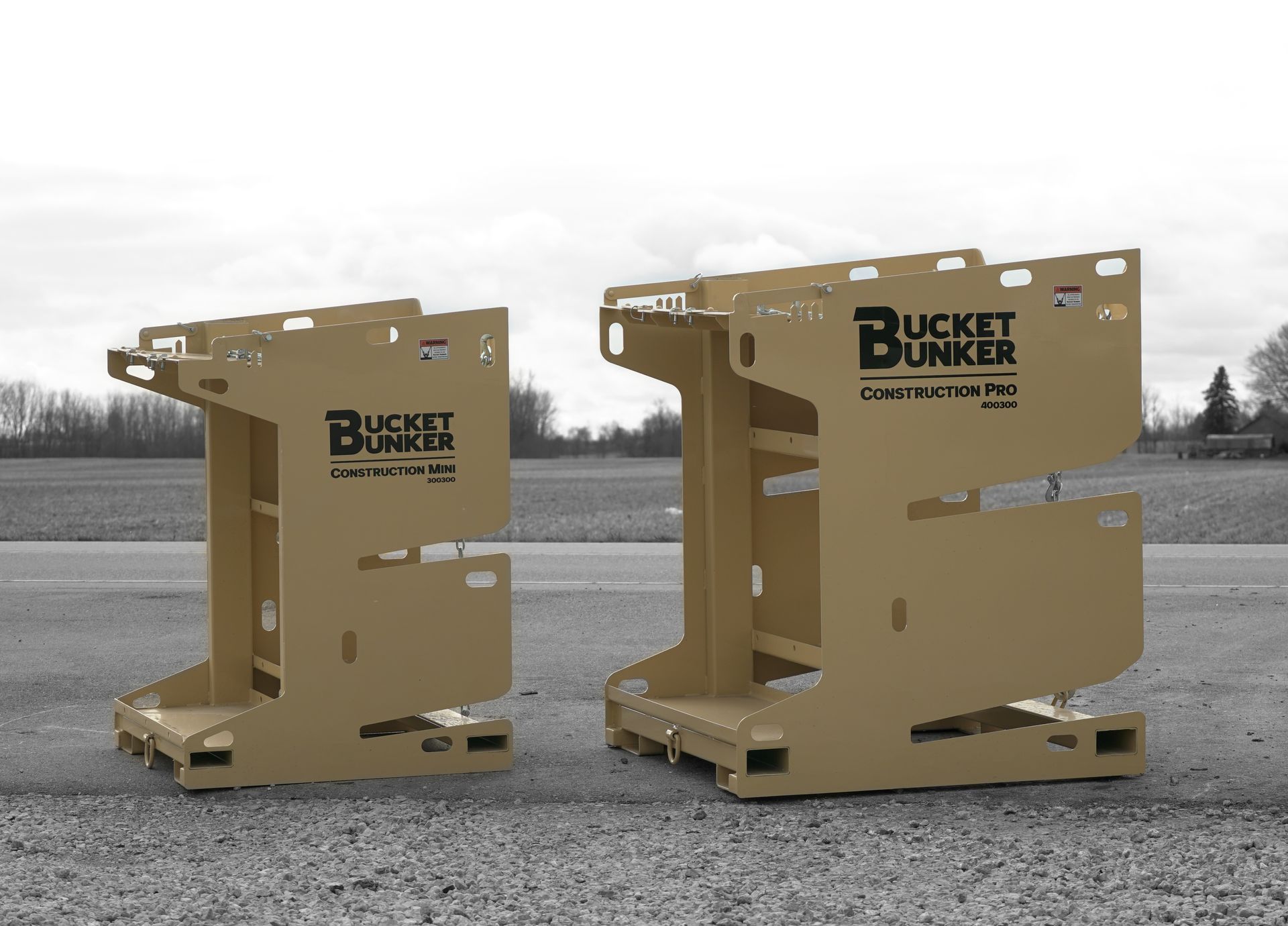 Two bucket bunkers are sitting next to each other on a gravel road.