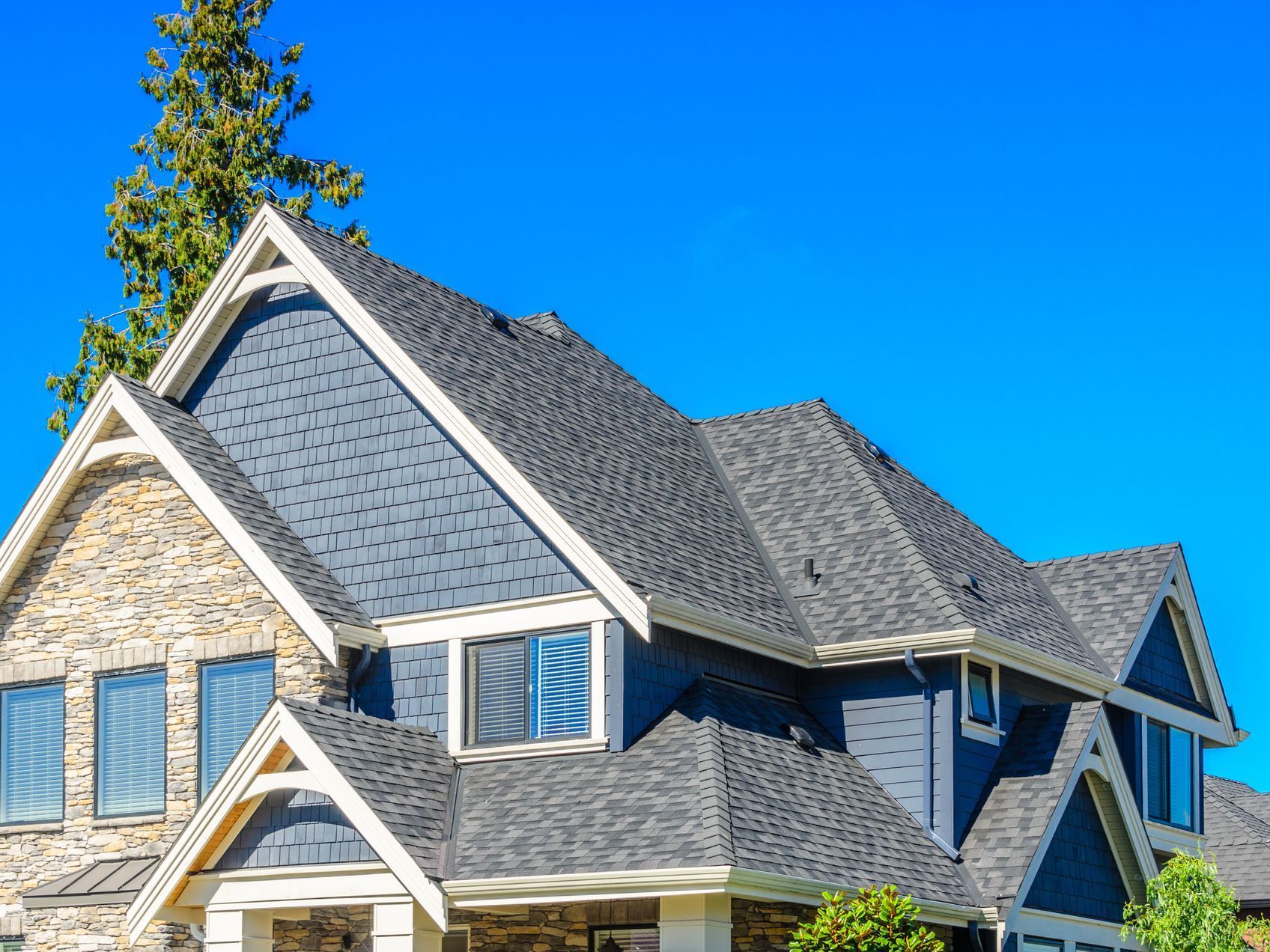 A large house with a gray roof and a blue sky in the background.
