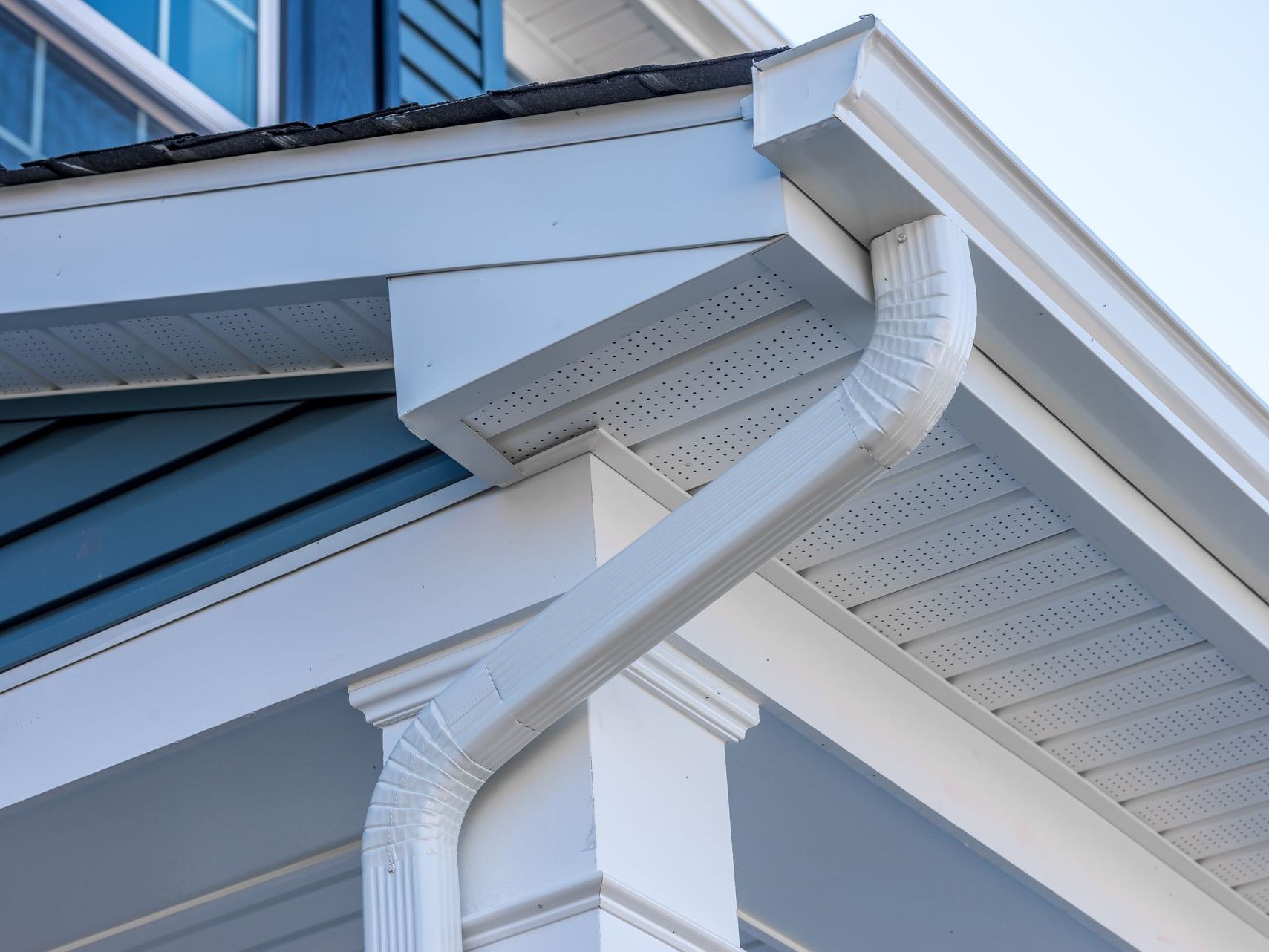 A close up of a white gutter on the side of a house.