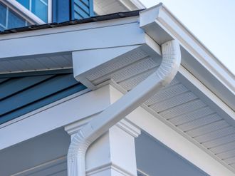 A close up of a white gutter on the side of a house.