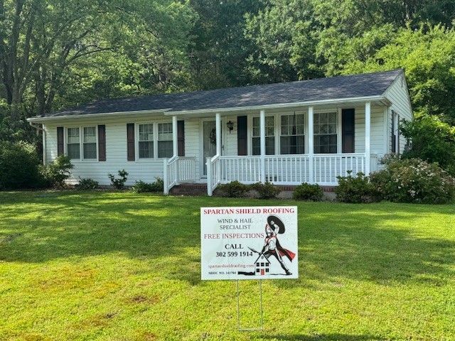 White house with porch; sign for home inspections in front.