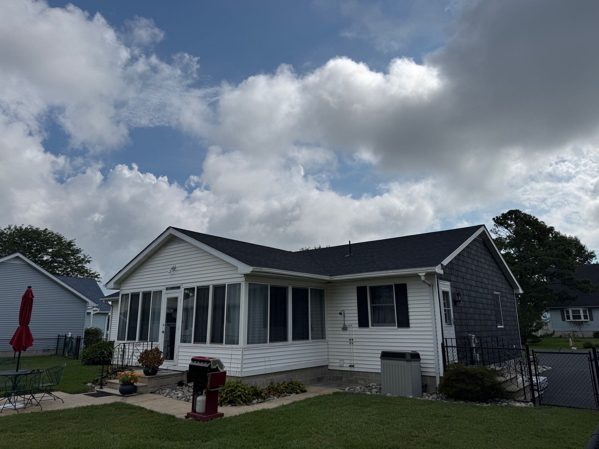 White bungalow with a dark roof under a cloudy sky.