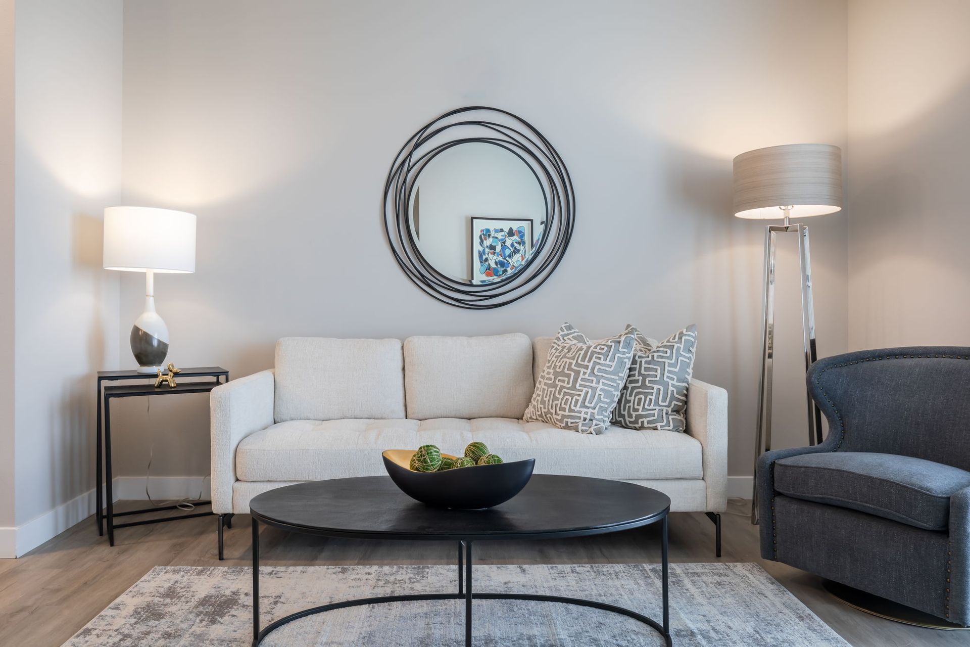 A living room with a couch , chair , coffee table and mirror.