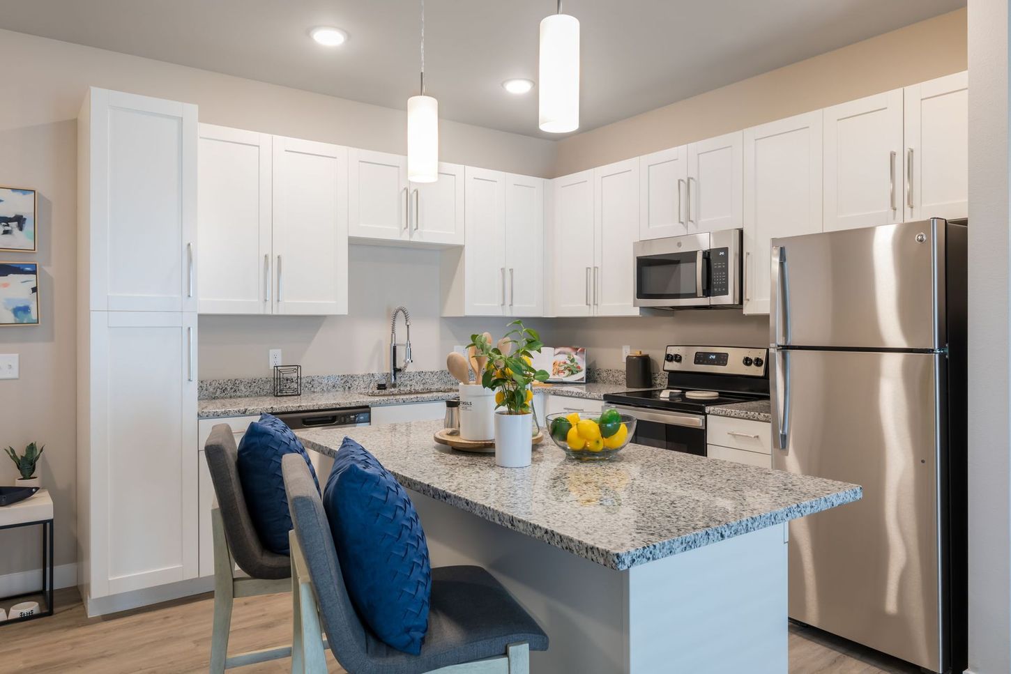 A kitchen with white cabinets , granite counter tops , stainless steel appliances and a stainless steel refrigerator.