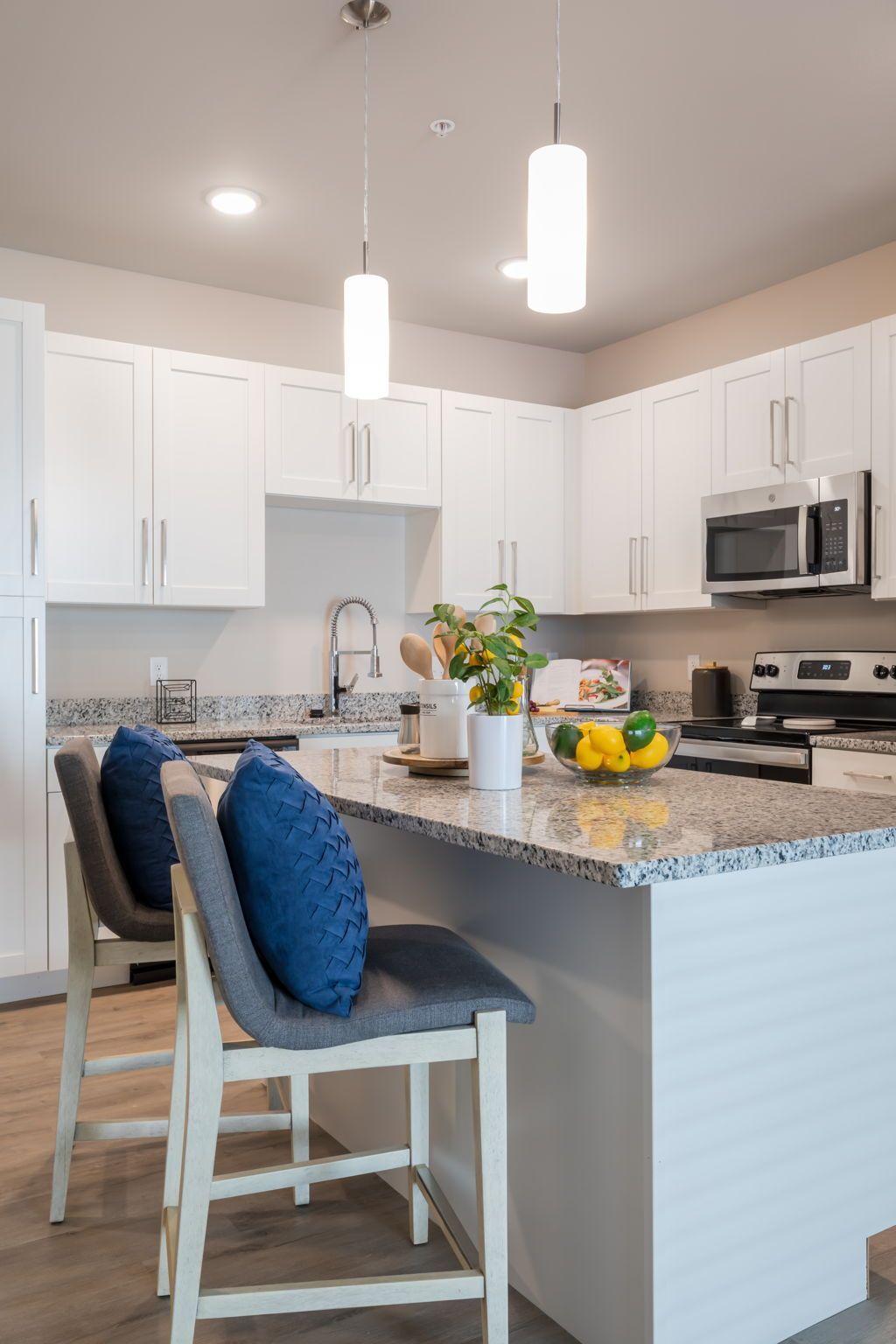 A kitchen with white cabinets , granite counter tops , stainless steel appliances and a large island.