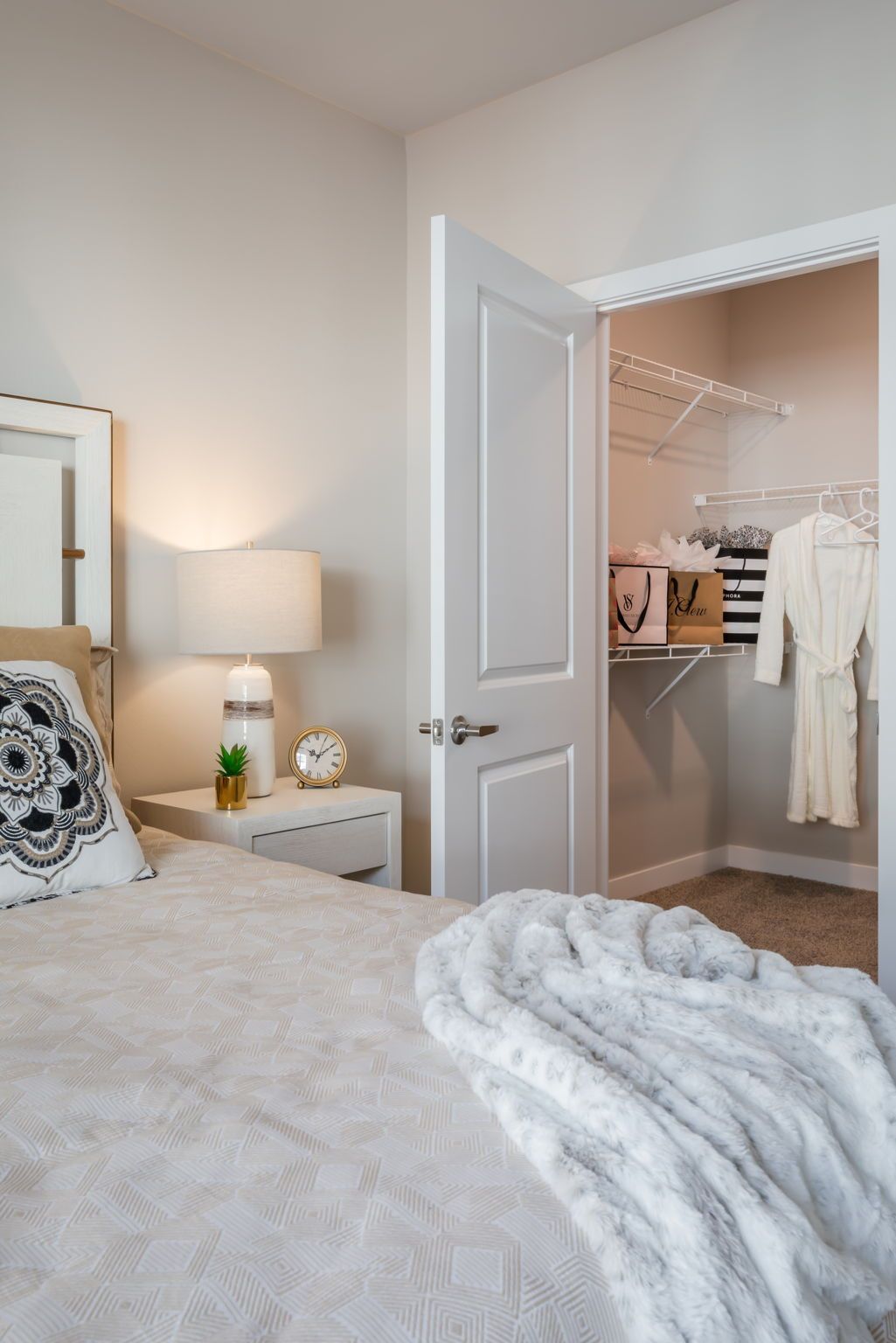 A bedroom with a bed , nightstand , lamp and walk in closet.