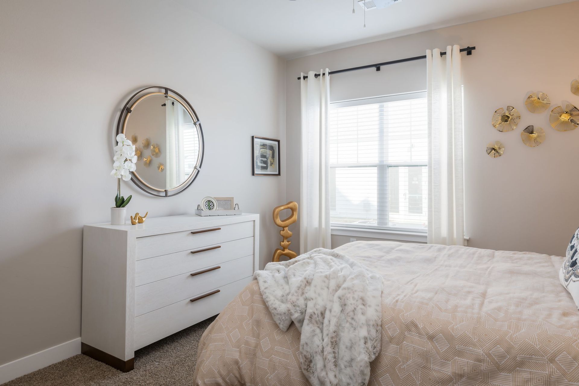 A bedroom with a bed , dresser , mirror and window.